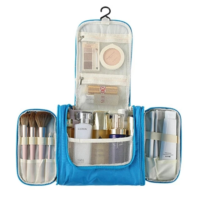 A blue multi-compartment travel pouch with a floral print lining, containing various makeup and beauty tools.