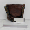 A dark brown leather geometric strap crossbody hobo bag resting on a white box.