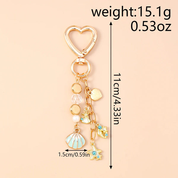 Gold heart-shaped keychain featuring a seashell and starfish charm with pearl accents