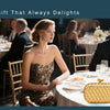 A woman in a gold sequined dress sits at a dinner table with a handwoven gold clutch bag.