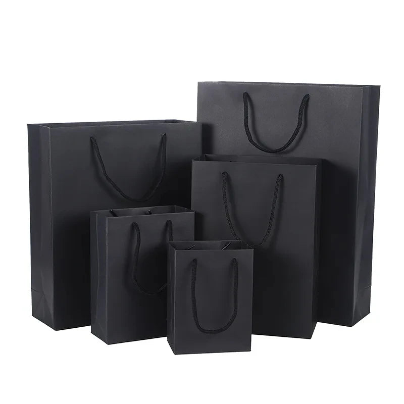 Un juego de bolsas de regalo de papel grueso negro con asas de cuerda, exhibidas sobre un fondo blanco.
