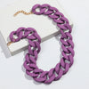 A purple matte acrylic chain necklace with a gold-colored clasp is displayed on a white box.