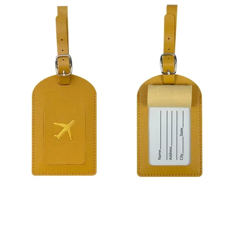 A pair of mustard yellow PU leather luggage tags with silver clasps and a beige card holder.