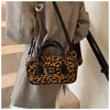 Eine braune Leopardenmuster-Designer-Hobo-Tasche hängt an einem grauen Blazer.