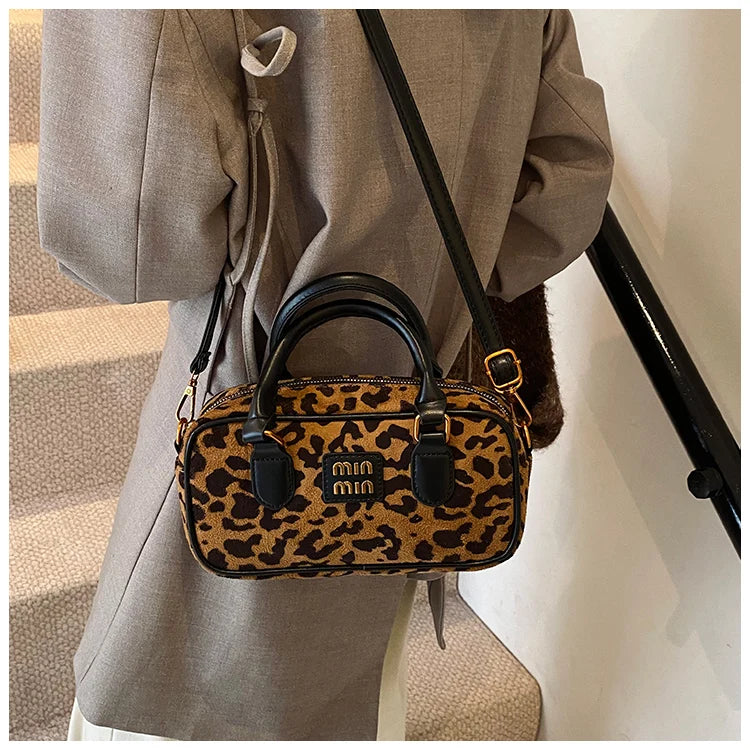 Eine braune Leopardenmuster-Designer-Hobo-Tasche hängt an einem grauen Blazer.