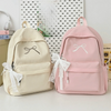 A pair of light beige and pink embroidered nylon backpacks for students displayed on a white surface.
