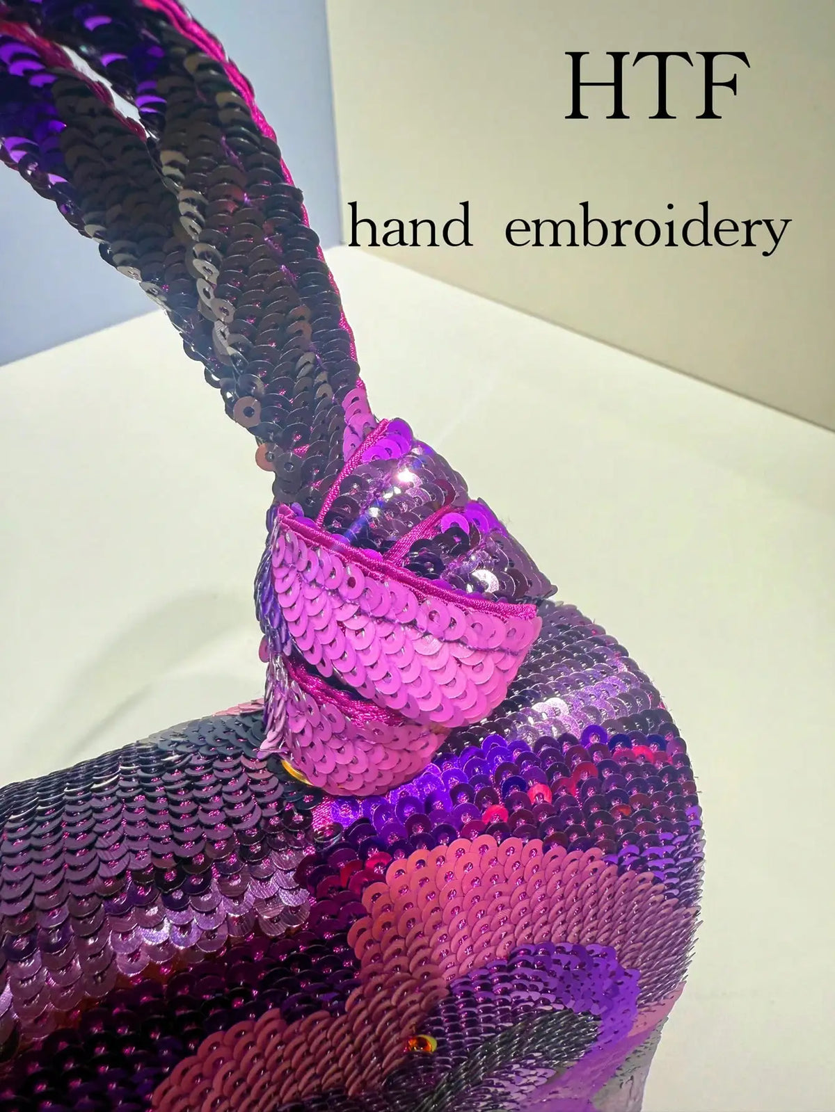 Close-up of a purple sequin embroidered clutch bag featuring floral patterns.