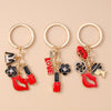 Three gold-toned enamel heart keychains featuring red lips and floral accents.