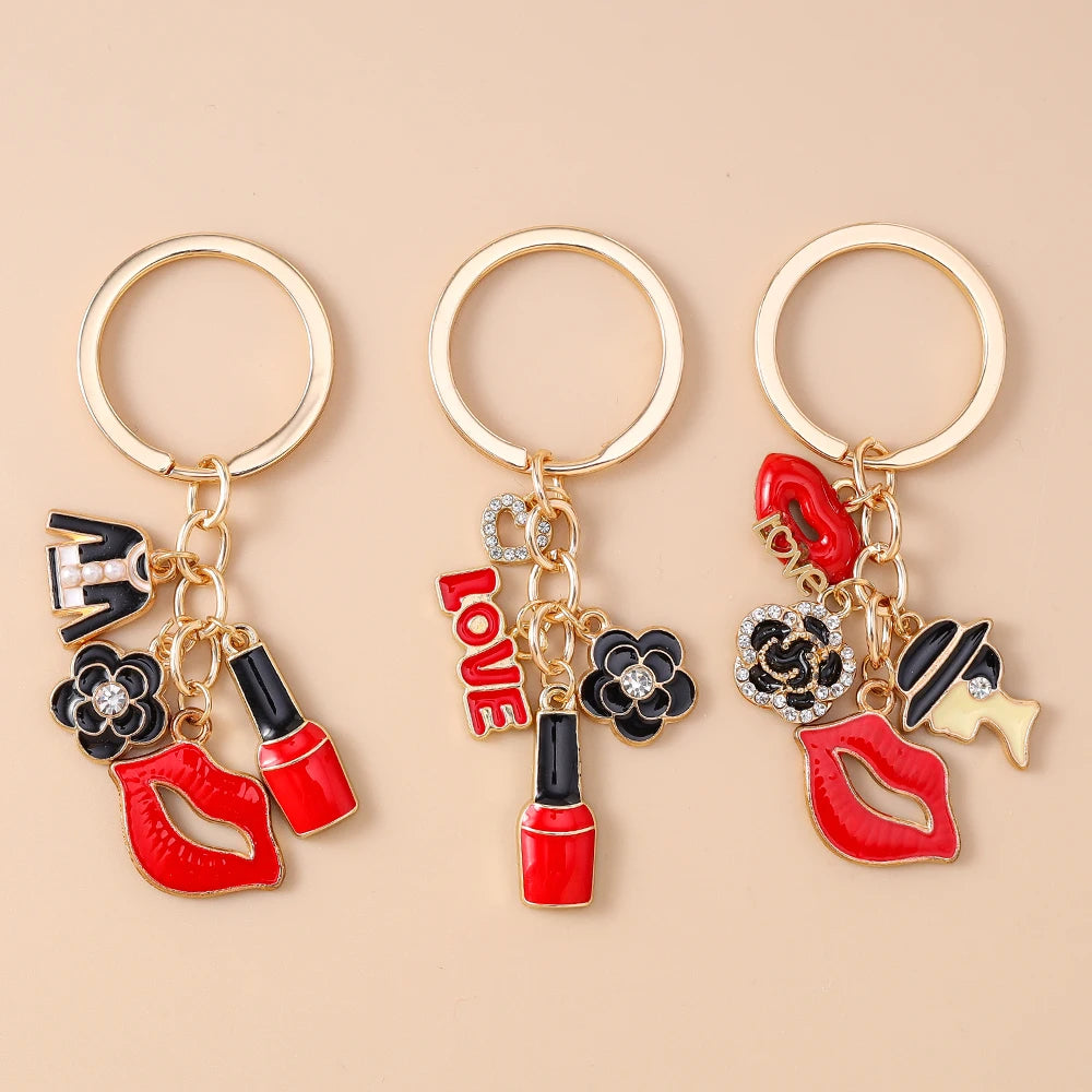 Three gold-toned enamel heart keychains featuring red lips and floral accents.