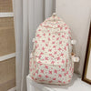 Mochila blanca con estampado floral de flores rosas y rojas y múltiples bolsillos.