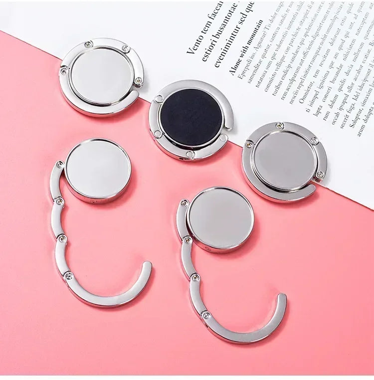 Ganchillo plegable plateado para organizar artículos en una mesa o bolso.
