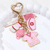 Gold keychain featuring a pink cartoon infusion pump and thermometer on a white background.