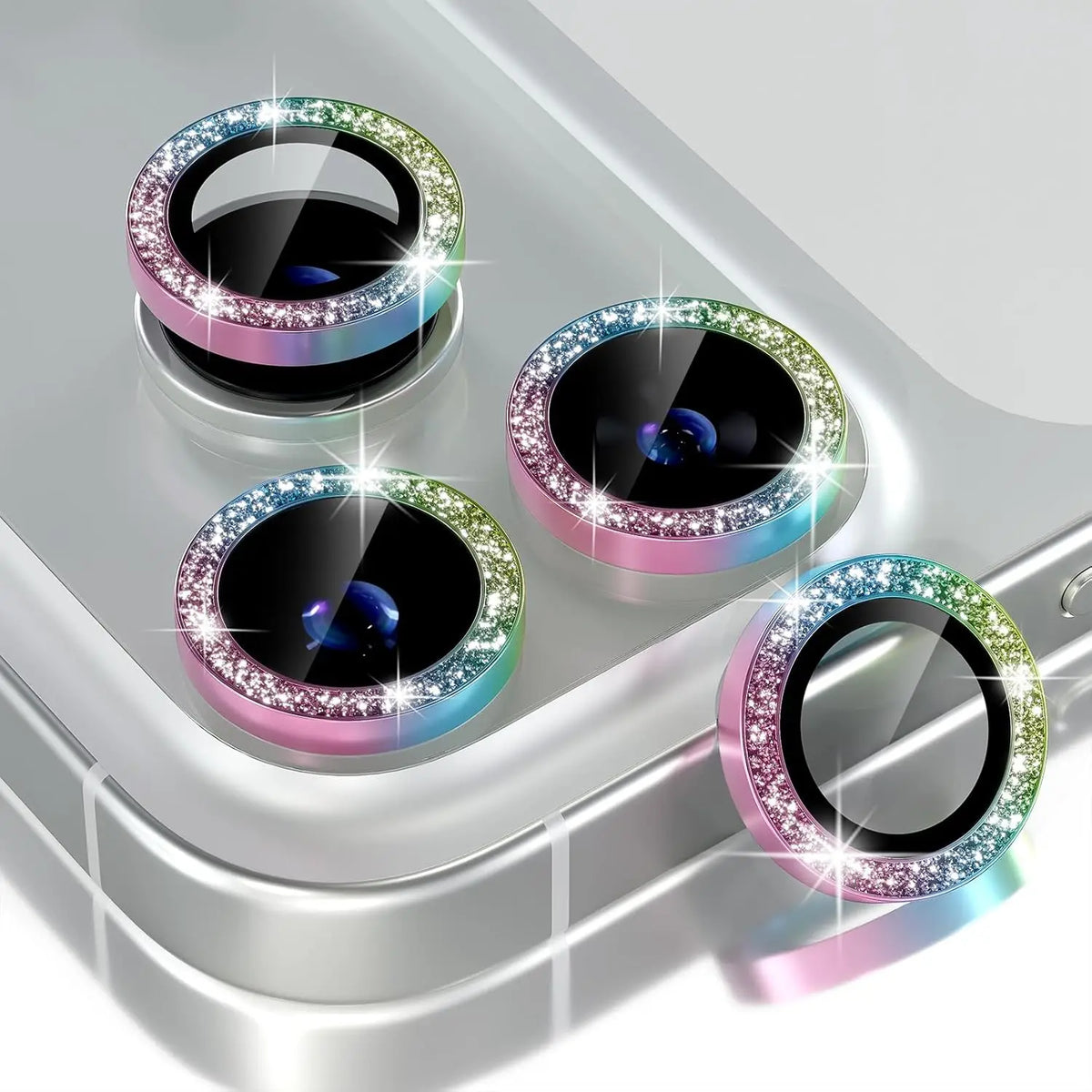 A collection of glitter diamond camera lens protectors with metal frames displayed on a silver surface.