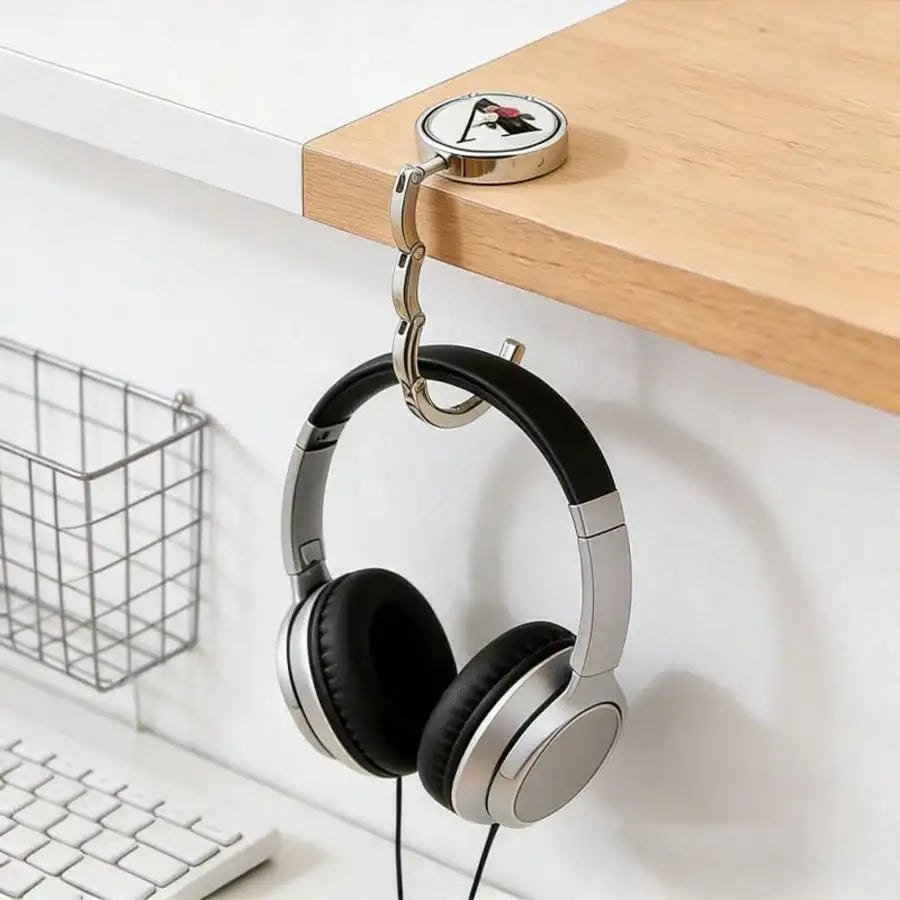 A pair of silver and black headphones hanging from a hook on a wooden shelf.