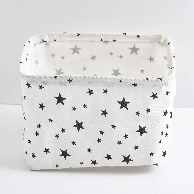 A white storage basket with a lid and handles decorated with small gray and black stars.