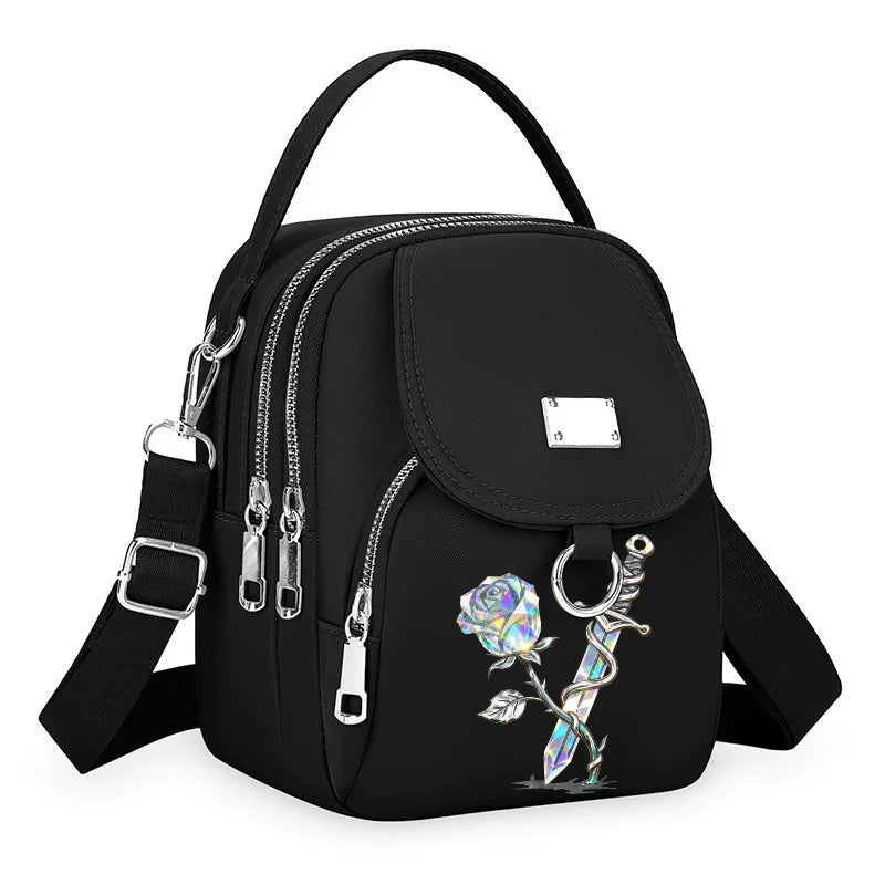 Sac bandoulière floral noir et durable avec fermeture éclair et quincaillerie argentée.