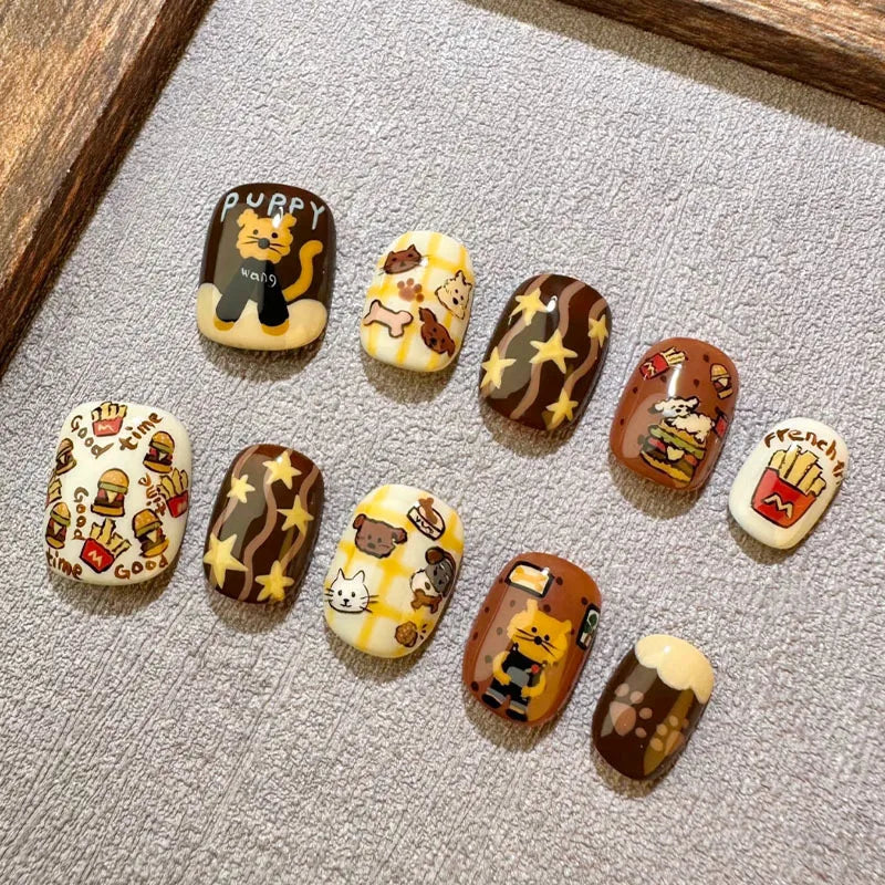 A collection of 12 cute cartoon press-on nails shaped like beans, featuring cats and other characters on a gray surface.