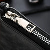Close-up of a black zippered pouch with a silver metal zipper pull and teeth.