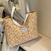 A beige bohemian corduroy tote bag with a floral pattern is held by a person.