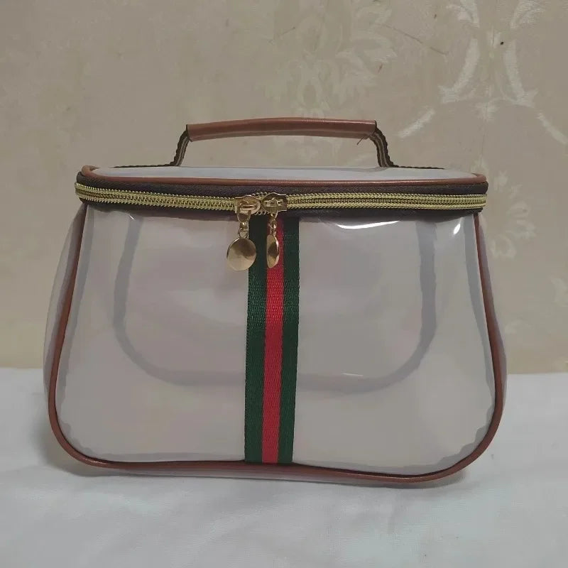 A transparent cosmetic bag with a brown trim and green and red stripes, featuring a gold zipper.