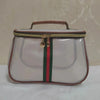 A transparent cosmetic bag with a brown trim and green and red stripes, featuring a gold zipper.