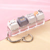 A row of pastel-colored kawaii cat keycaps arranged in a clear plastic holder with a silver bag charm.