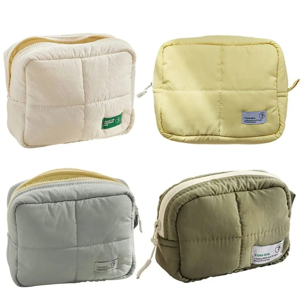 Three quilted puffer makeup bags in cream, yellow, and olive green colors.