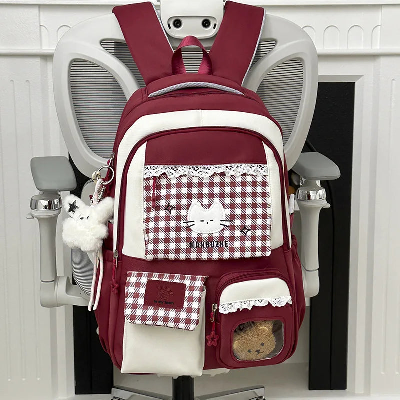 A maroon and white backpack featuring a laptop compartment and decorative lace details.