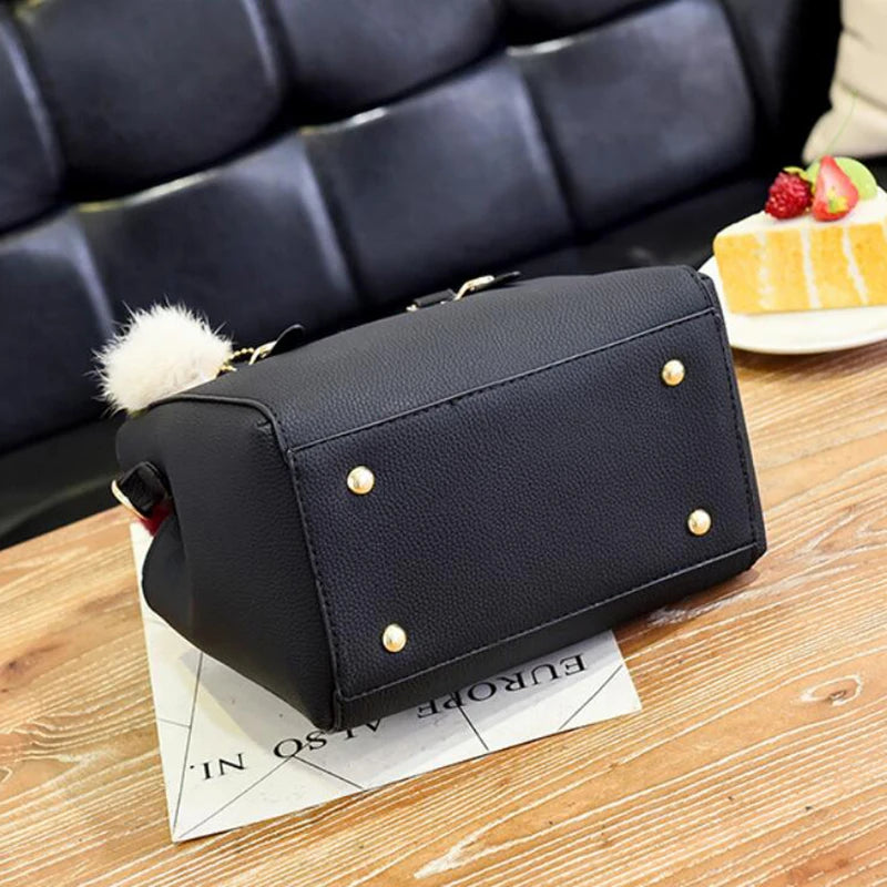 A black vintage PU leather tassel handbag resting on a wooden surface next to a piece of cake.