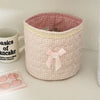 Cesta de almacenamiento de corazón acolchado rosa de algodón con ribete de encaje, junto a una taza y artículos rosas.