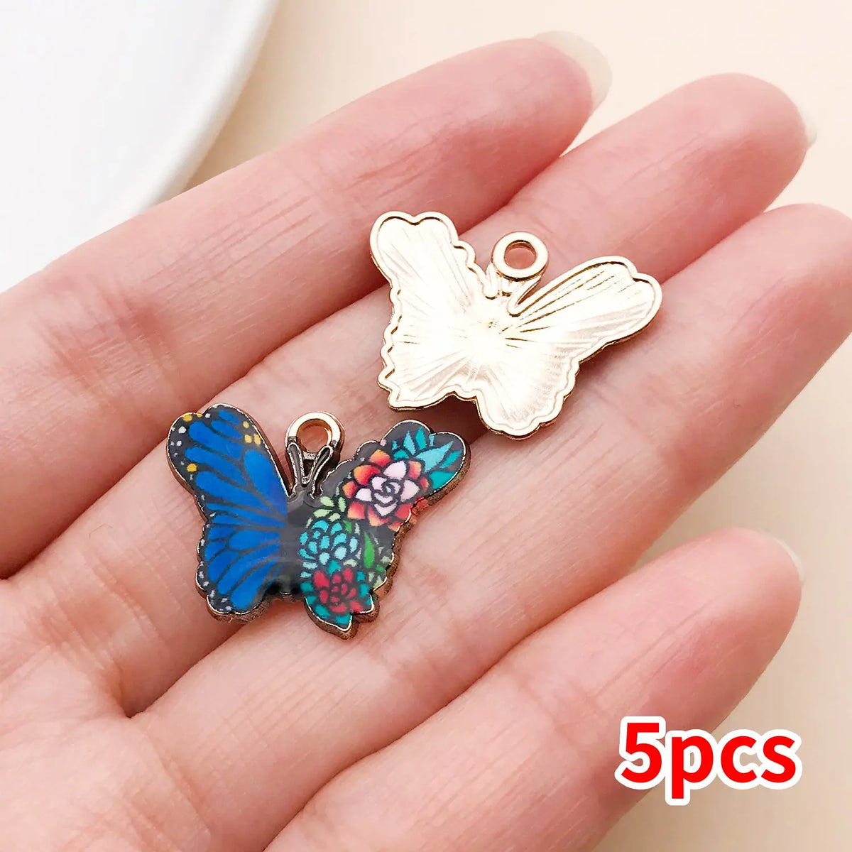 A hand holds a set of five colorful butterfly enamel charms on a silver-toned jewelry ring.