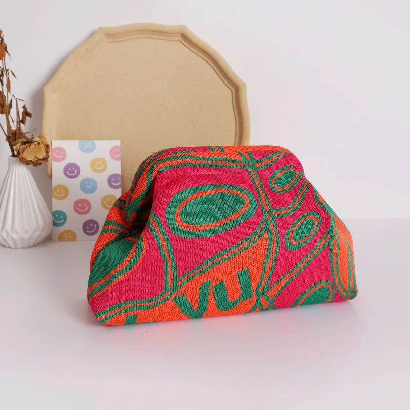 A vibrant knitted clip bag with an orange and pink pattern rests in front of a beige cardstock shape.
