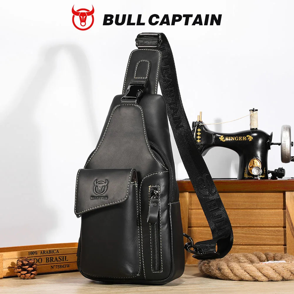 A black genuine leather sling backpack with a leather strap and pocket displayed on a wooden surface.