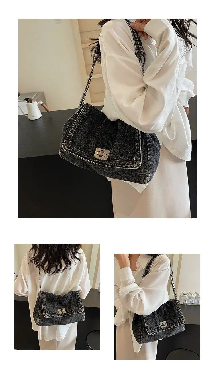A woman holds a dark denim tote bag with a chain strap against a light background.