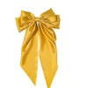 A golden yellow silk bow used as a hair accessory or clip.