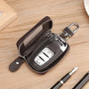 A dark brown leather car key case with a transparent window and silver clasp resting on a wooden surface.