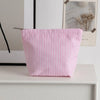 Pochette en crochet rayée rose et blanc posée sur une étagère blanche à côté d'un tableau encadré.