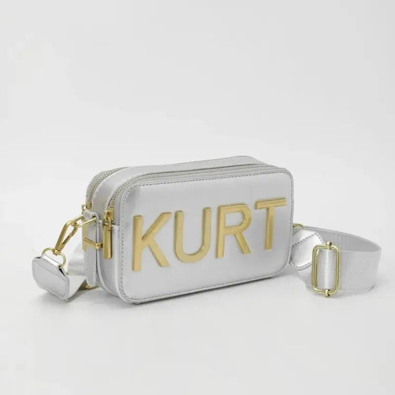 Silver leather pouch bag with gold lettering and a white strap