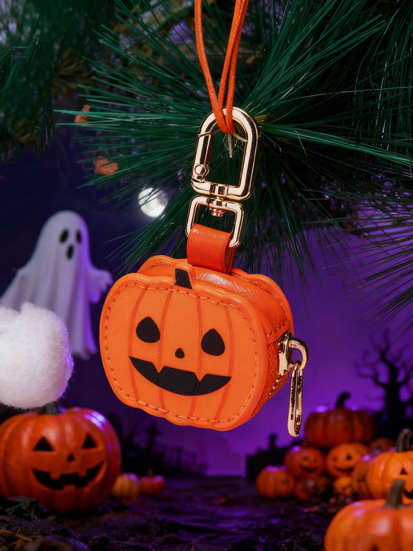 An orange pumpkin-shaped mini PU leather keychain accessory hanging from a green pine branch.