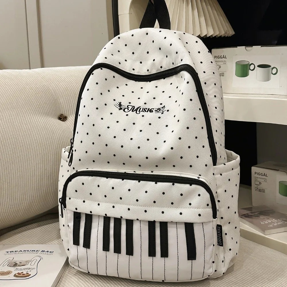 Sac à dos blanc à pois noirs et bordure noire, avec un motif de note musicale.