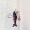 A purple simulation fish keychain with iridescent accents hanging from a thin string.