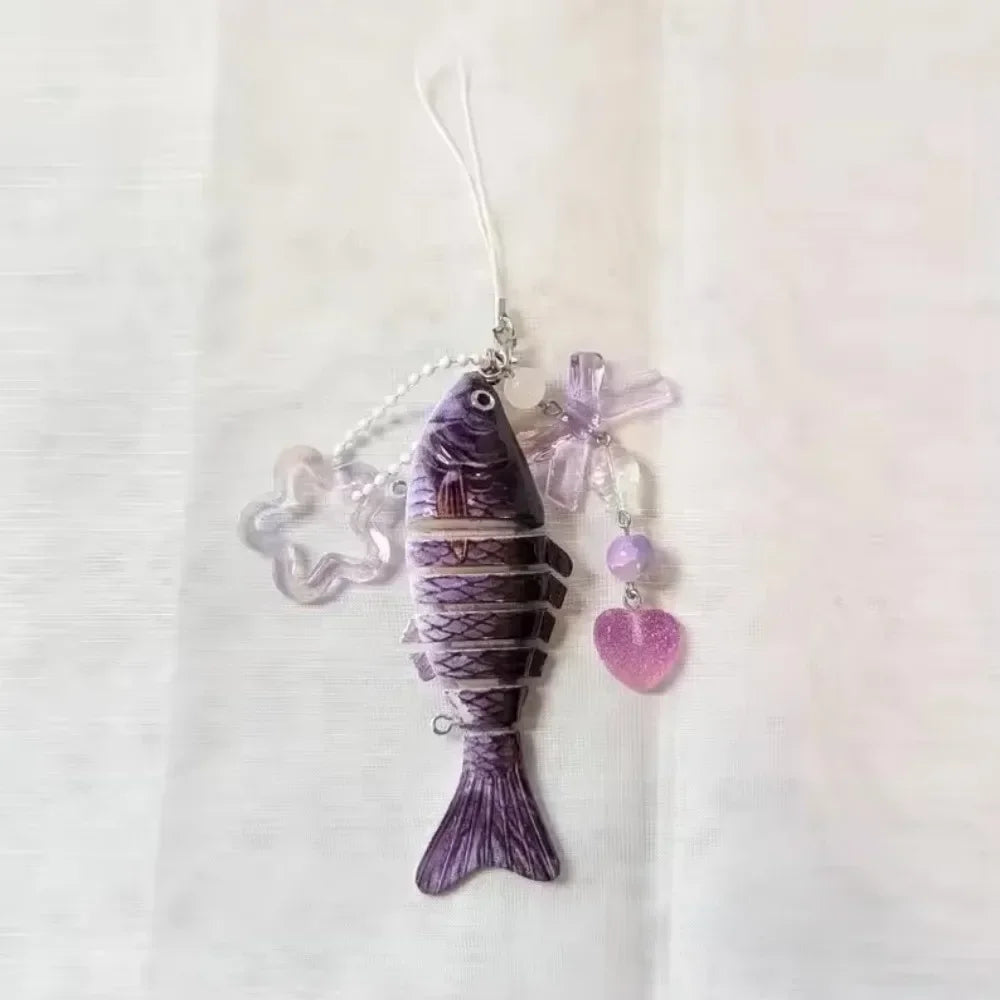 A purple simulation fish keychain with iridescent accents hanging from a thin string.