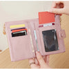 A close-up of a pink leather foldable wallet with a zipper and card slots being held by a woman.