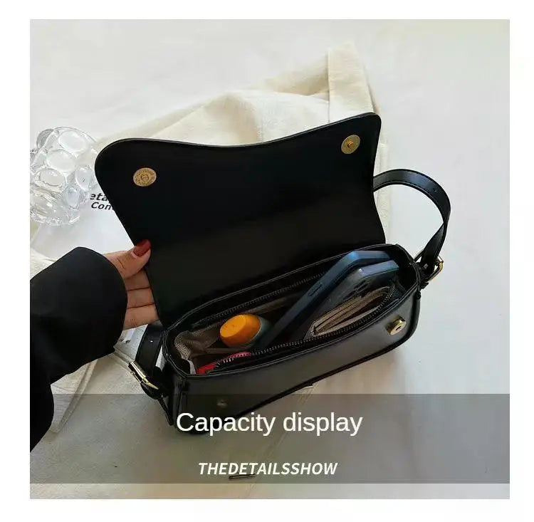 Bolso cruz de cuero negro estilo vintage, abierto mostrando su interior y capacidad.