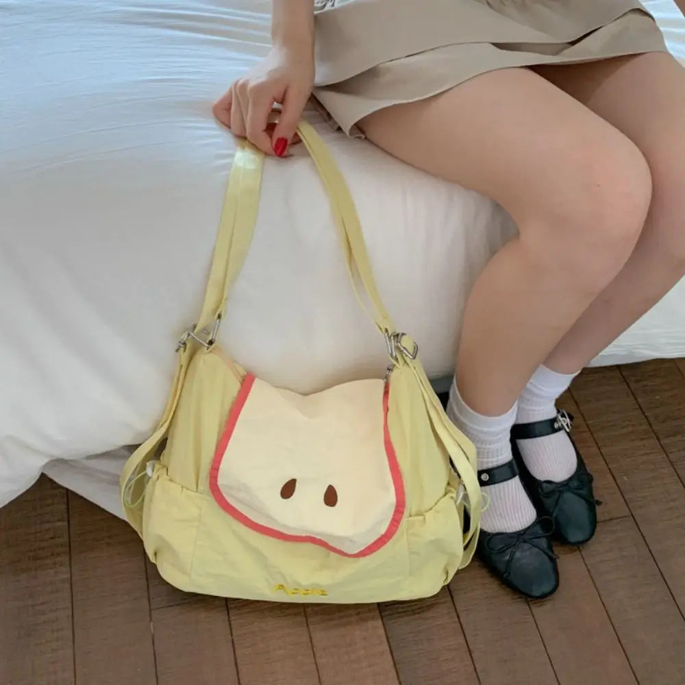 A woman wearing a beige skirt is holding a yellow nylon messenger backpack.