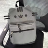A gray Pusheen cat canvas backpack with black whiskers and eyes resting on a black chair.