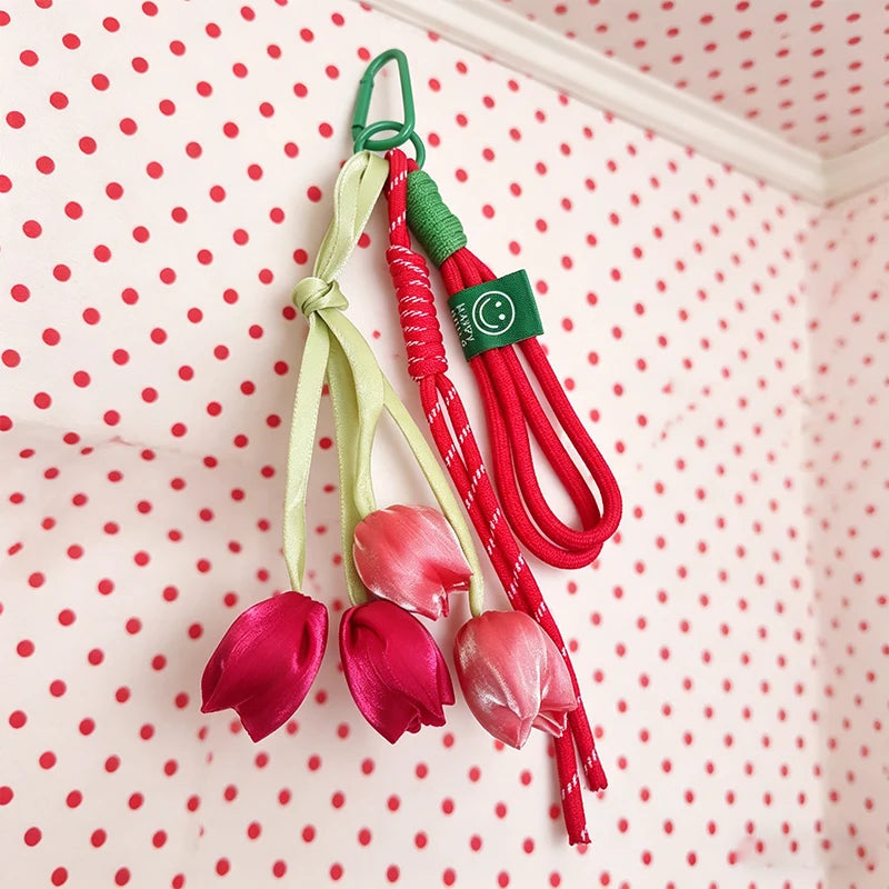 A set of red and green aesthetic tulip flower bag charm keychains hanging against a white polka dot background.