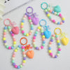 A collection of colorful bead keychains featuring heart shapes and bows on silver O-ring clips.