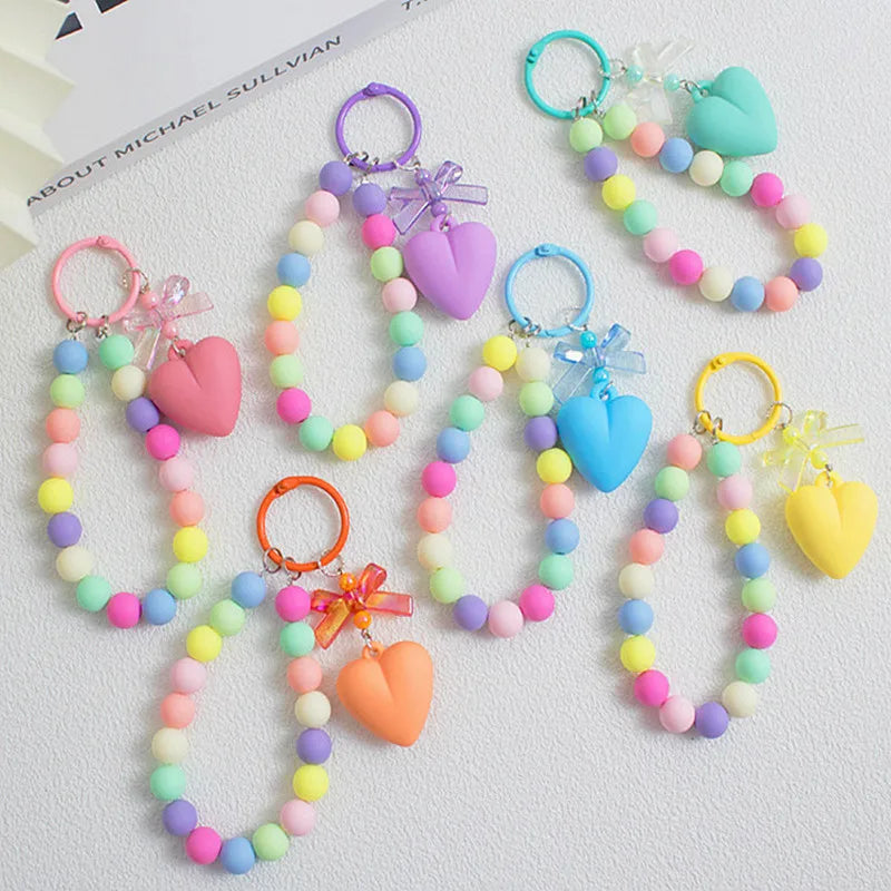 A collection of colorful bead keychains featuring heart shapes and bows on silver O-ring clips.