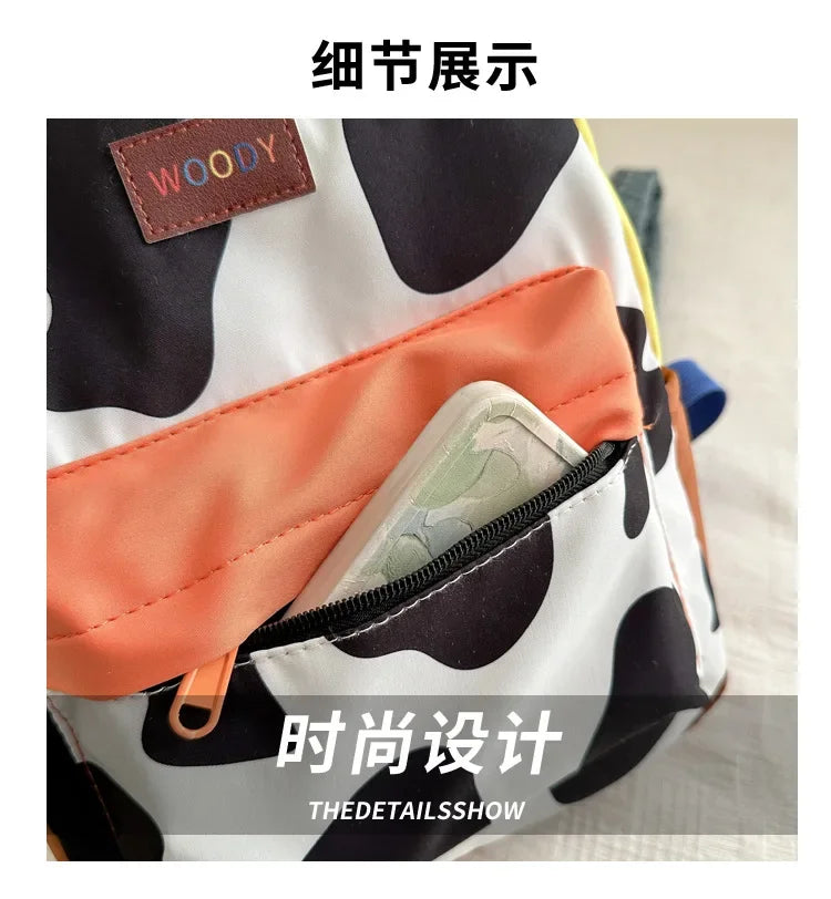 Close-up detail of a white and black cow print fashion backpack showing the interior lining and a leather tag.